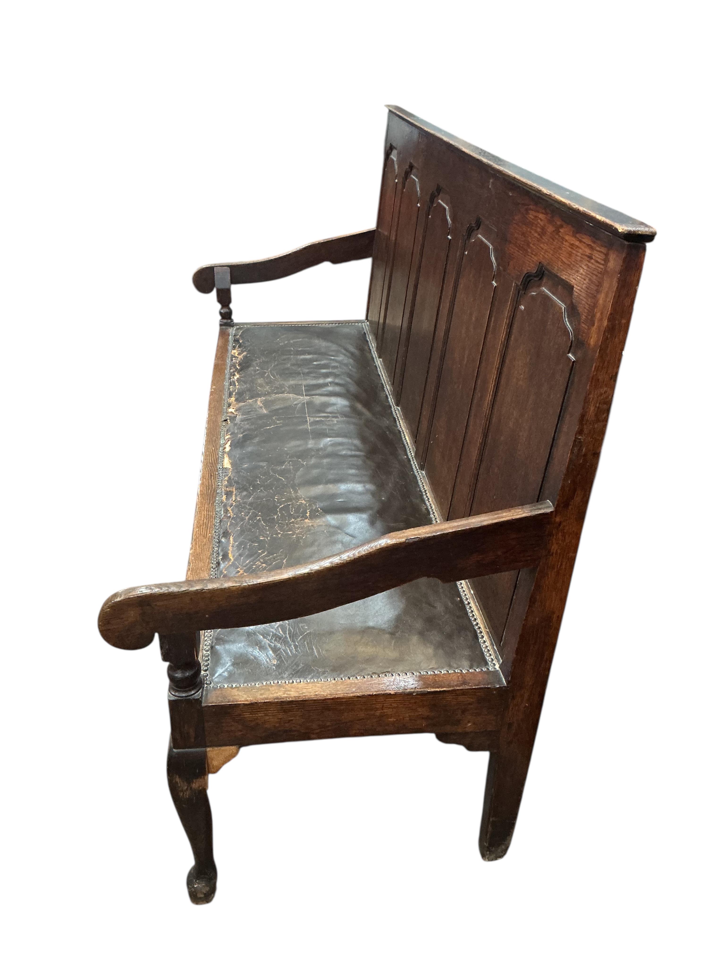 A George III panelled oak settle on cabriole front legs, width 185cm, depth 65cm, height 106cm
